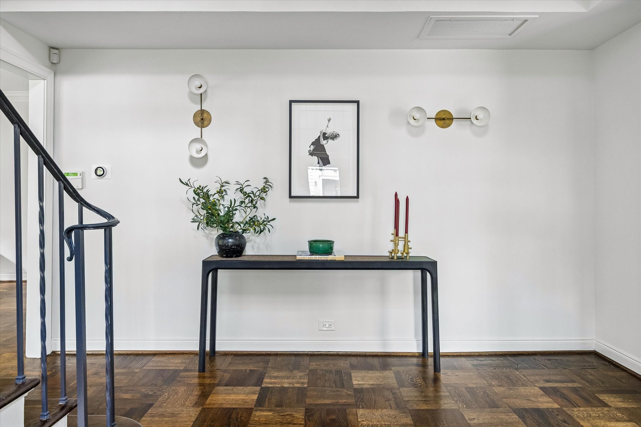 2133 Inwood Drive Houston, TX 77019 - Photo 4 of 22 This elegant foyer features a minimalist design. The space is complemented by modern wall sconces, set against a backdrop of white walls and rich wooden parquet flooring.