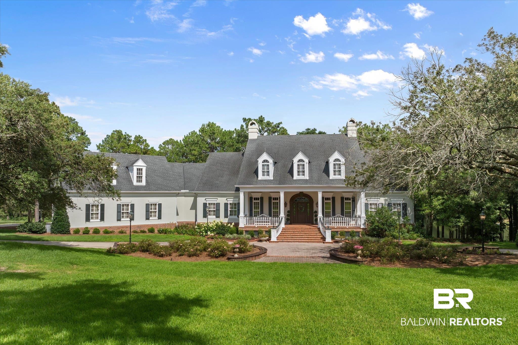 Cape cod house with covered porch, a front yard, and a chimney