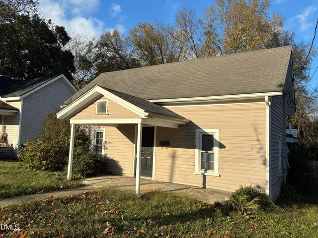 a view of a white house with a small yard and potted plants