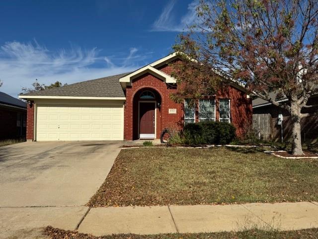 Single story home with a garage, concrete driveway, brick siding, and a front yard
