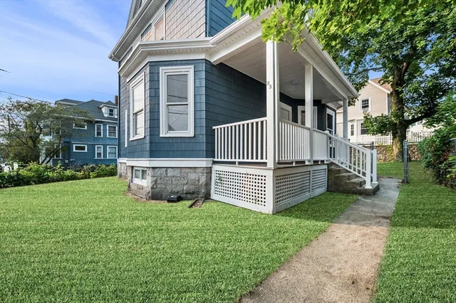 a view of a house with a yard plants and large tree