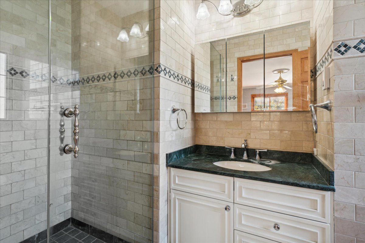 203 Pine Street Deerfield, IL 60015 - Photo 13 of 24 a bathroom with a granite countertop sink a mirror and shower
