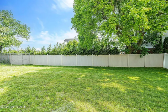 a view of a backyard with a fence and trees