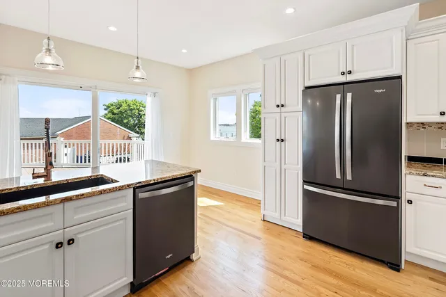 a kitchen with granite countertop stainless steel appliances a refrigerator cabinets and wooden floor