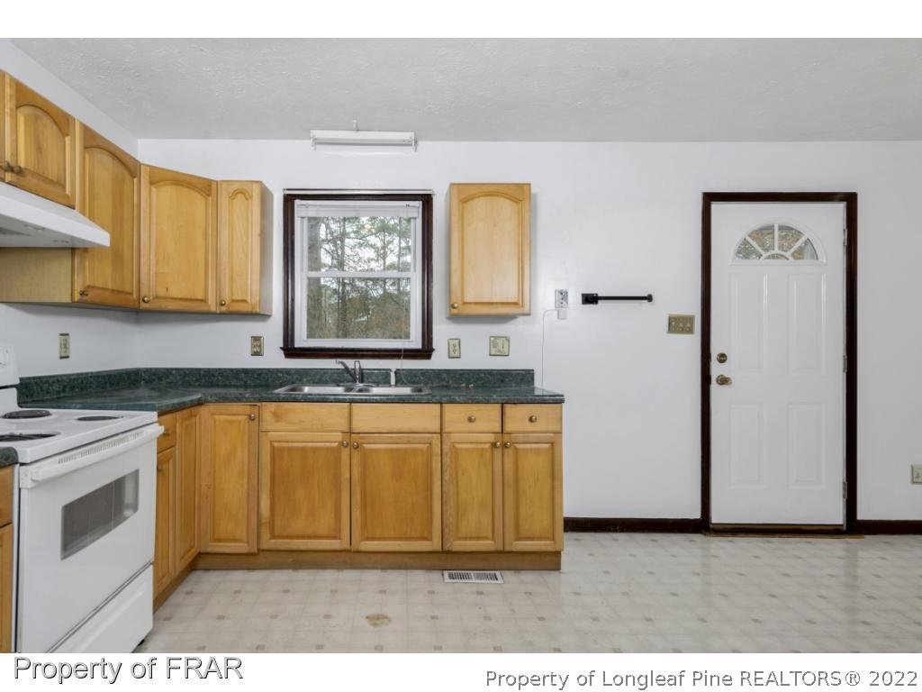 1758 Rim Road Fayetteville, NC 28314 - Photo 10 of 25 a kitchen with stainless steel appliances granite countertop a stove a sink and a microwave