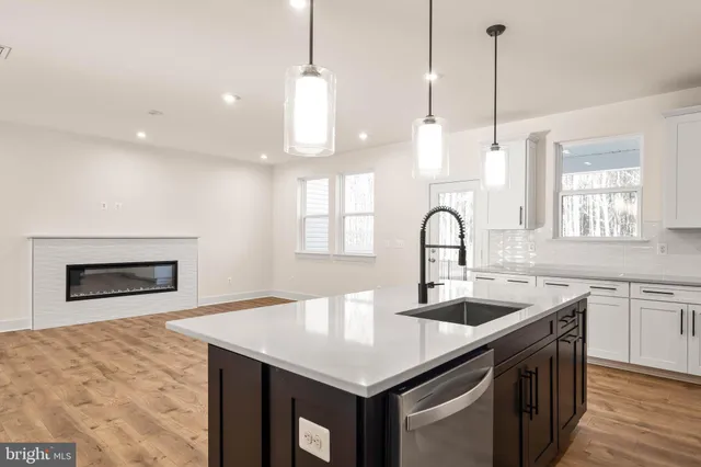 a kitchen with stainless steel appliances granite countertop a sink a stove and a wooden floor