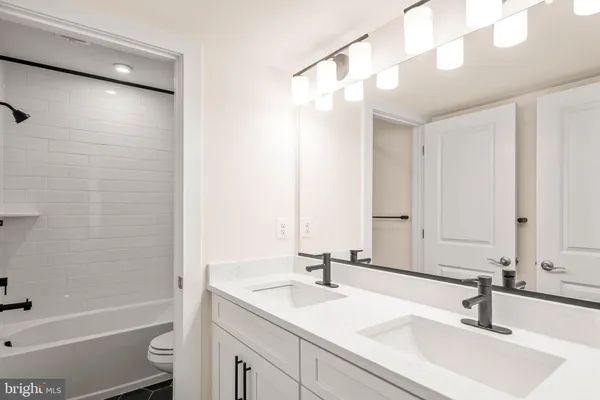 a bathroom with a sink double vanity granite tub shower and a mirror