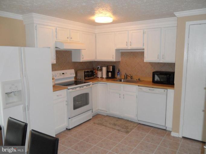 5057 Clifford Road Perry Hall, MD 21128 - Photo 6 of 13 a kitchen with stainless steel appliances white cabinets and a refrigerator