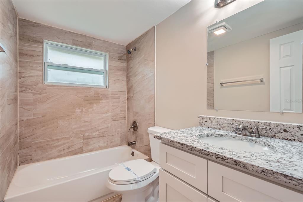 5429 Flora Avenue Holiday, FL 34690 - Photo 28 of 33 a bathroom with a granite countertop sink a toilet and bathtub