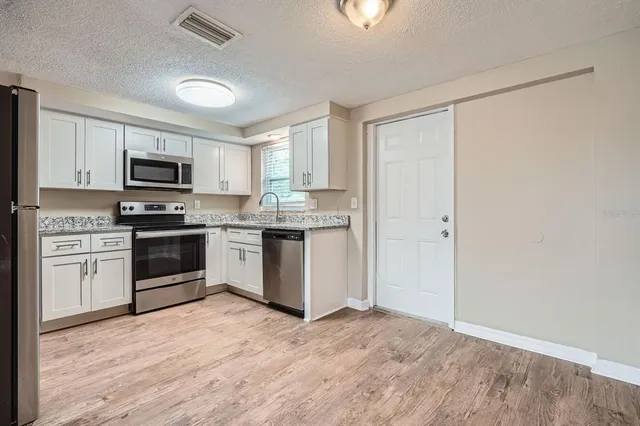 a kitchen with granite countertop a refrigerator and a stove top oven