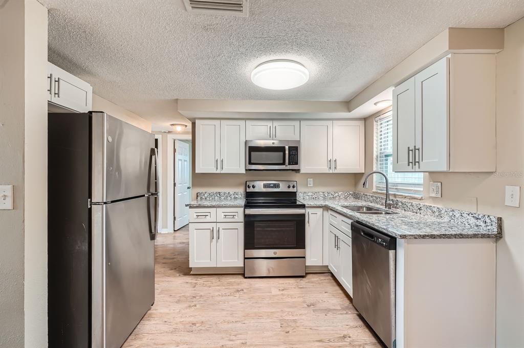 5429 Flora Avenue Holiday, FL 34690 - Photo 5 of 33 a kitchen with stainless steel appliances granite countertop a refrigerator stove and microwave