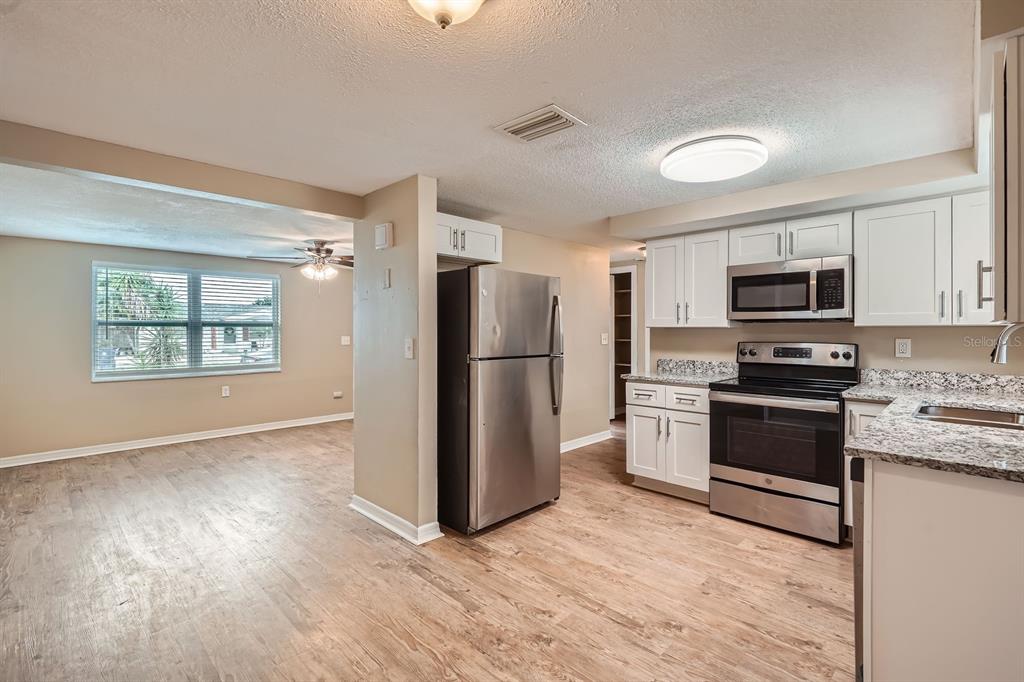5429 Flora Avenue Holiday, FL 34690 - Photo 6 of 33 a kitchen with granite countertop a refrigerator stove and microwave