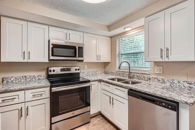 a kitchen with granite countertop white cabinets and appliances