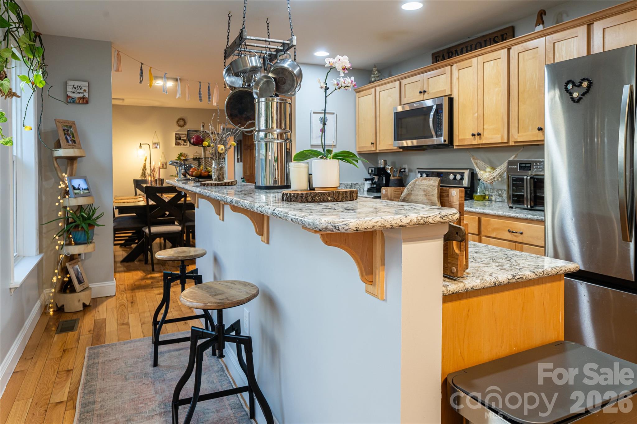 65 Owenby Road Candler, NC 28715 - Photo 25 of 48 a kitchen with stainless steel appliances kitchen island granite countertop a refrigerator a stove top oven a sink dishwasher and dining table with wooden floor