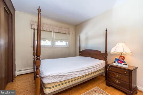 a bedroom with a bed and dresser with wooden floor