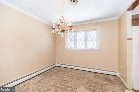 an empty room with a chandelier fan and windows