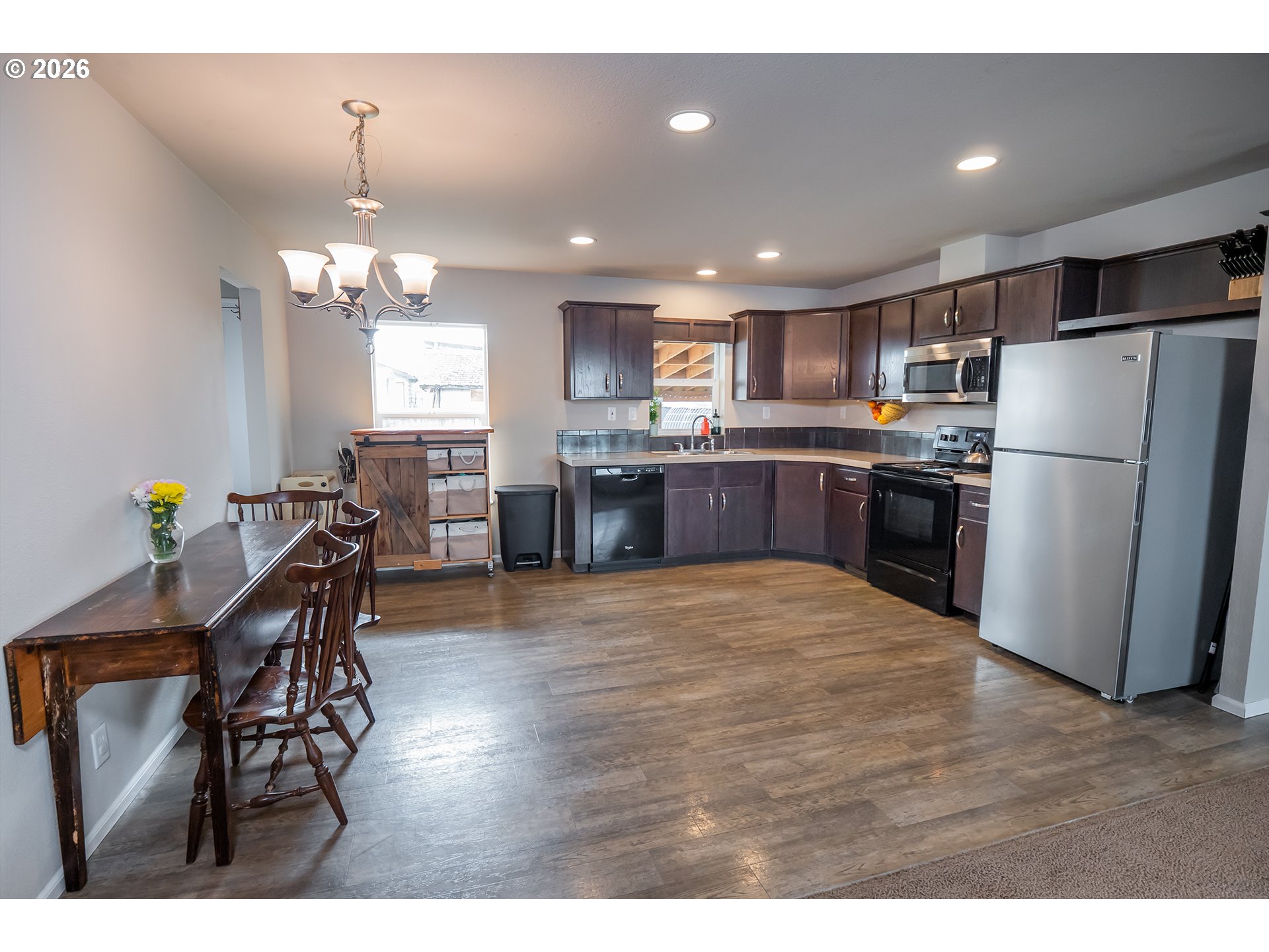 628 Stanley Lane Harrisburg, OR 97446 - Photo 9 of 32 a kitchen with stainless steel appliances kitchen island granite countertop a refrigerator a stove a sink a dining table and chairs with wooden floor