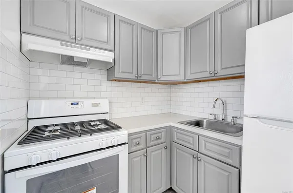 a white kitchen with granite countertop stainless steel appliances