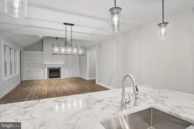 a kitchen with kitchen island granite countertop a sink cabinets and wooden floor