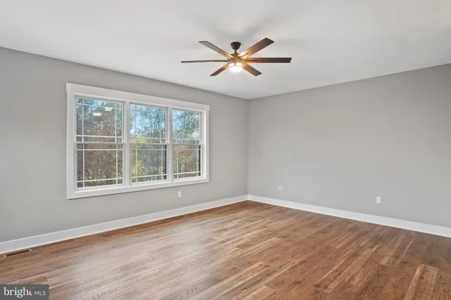 a view of an empty room with window and wooden floor