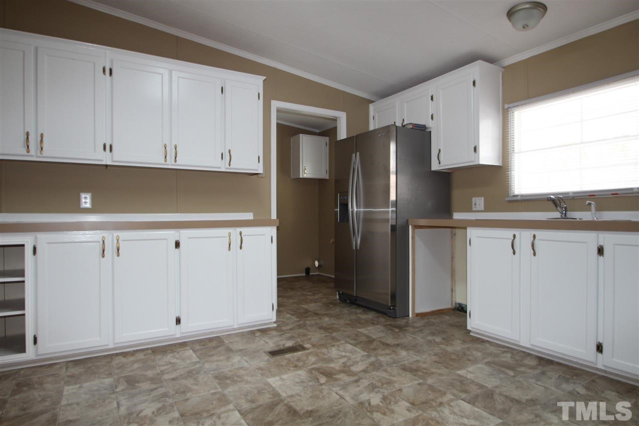 465 Melton Road Roxboro, NC 27574 - Photo 4 of 11 a kitchen with granite countertop white cabinets and refrigerator
