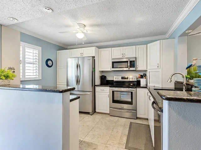 a kitchen with granite countertop white cabinets and stainless steel appliances