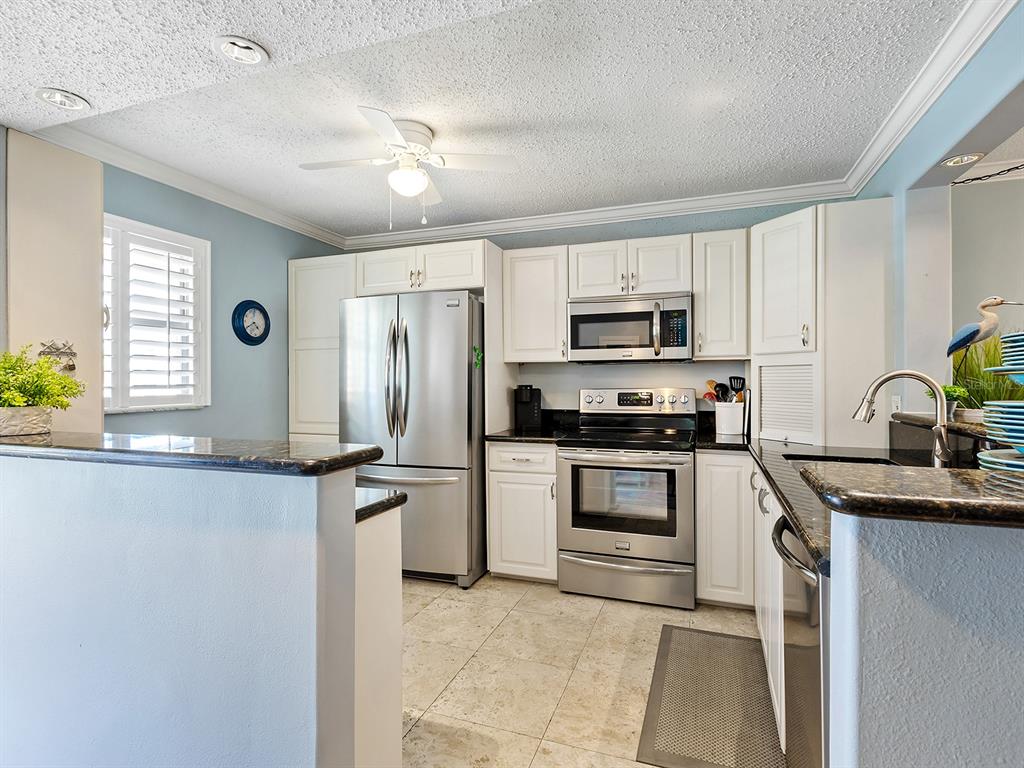 230 Santa Maria Street, Unit 234 Venice, FL 34285 - Photo 11 of 60 a kitchen with granite countertop a stove sink and microwave