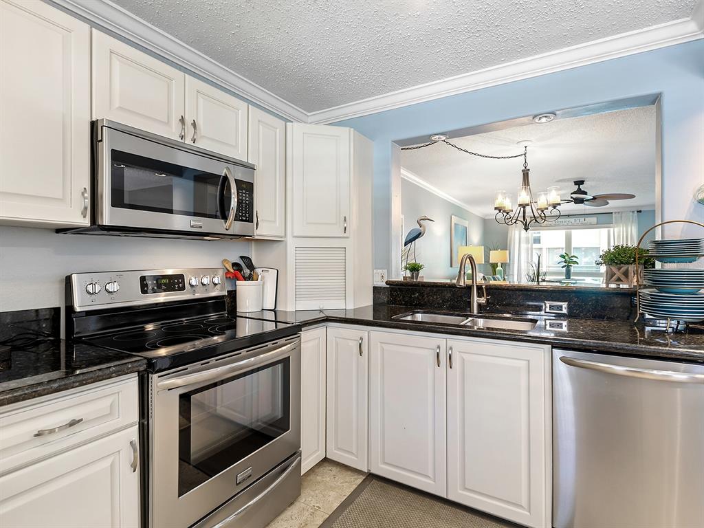 230 Santa Maria Street, Unit 234 Venice, FL 34285 - Photo 13 of 60 a kitchen with granite countertop white cabinets and stainless steel appliances