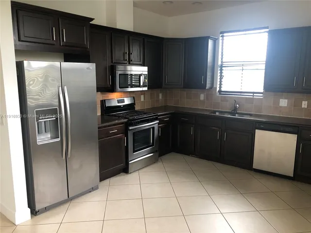 a kitchen with granite countertop wooden cabinets and stainless steel appliances