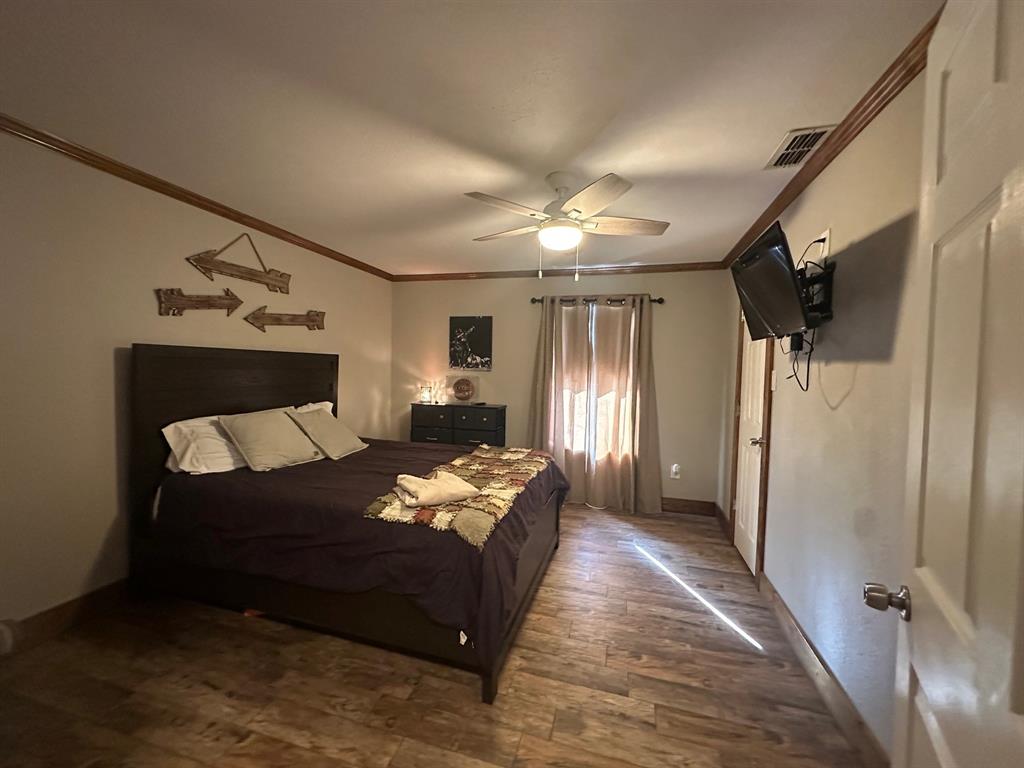 101 Twin Creek Road Comanche, TX 76442 - Photo 22 of 28 a bedroom with bed dresser and a chandelier