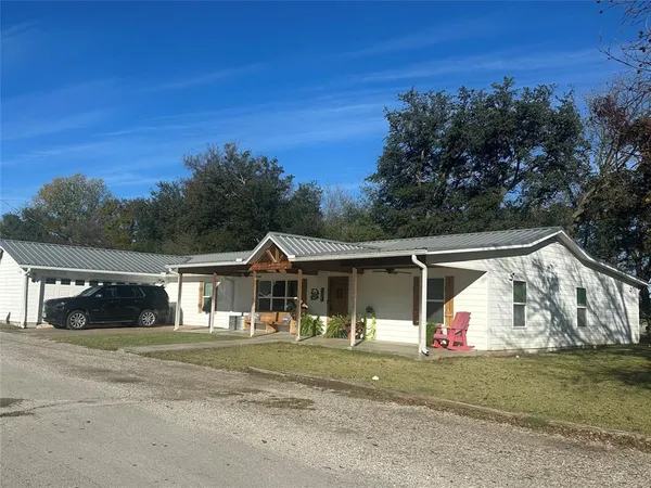 a front view of a house with a yard and trees