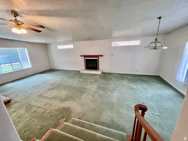 479 East 100 N Road Meadow, UT 84644 - Photo 7 of 59 Unfurnished living room with carpet, a tile fireplace, a ceiling fan, and a textured ceiling