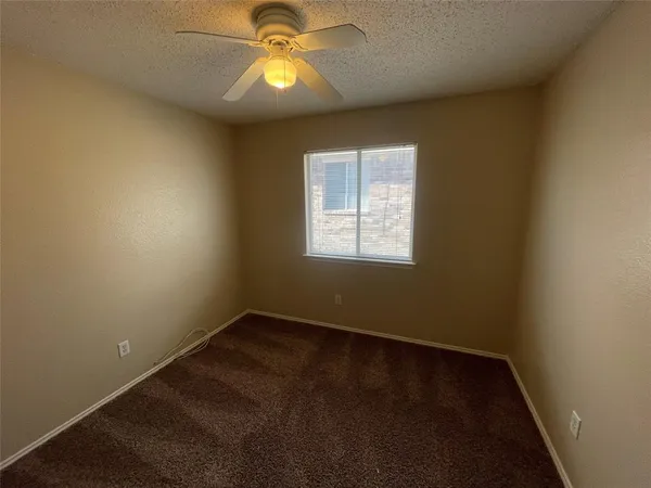 an empty room with a window and chandelier fan