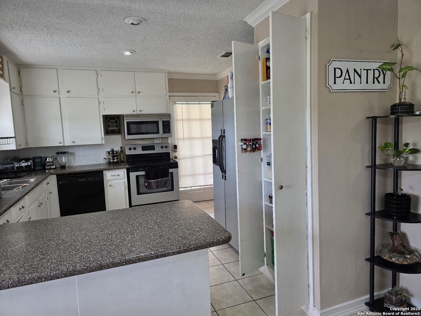932 South Getty Street Uvalde, TX 78801 - Photo 9 of 17 a kitchen with stainless steel appliances granite countertop a refrigerator and a sink