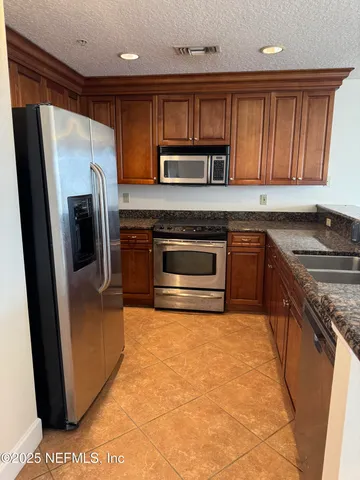 a kitchen with stainless steel appliances granite countertop a refrigerator stove and sink