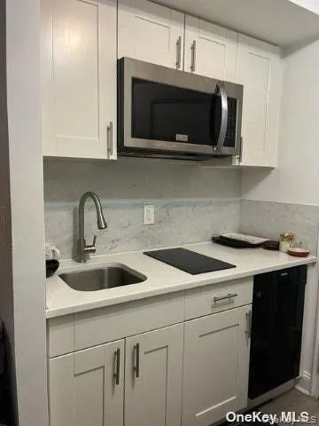 a kitchen with stainless steel appliances granite countertop a sink a microwave stove and white cabinets with wooden floor