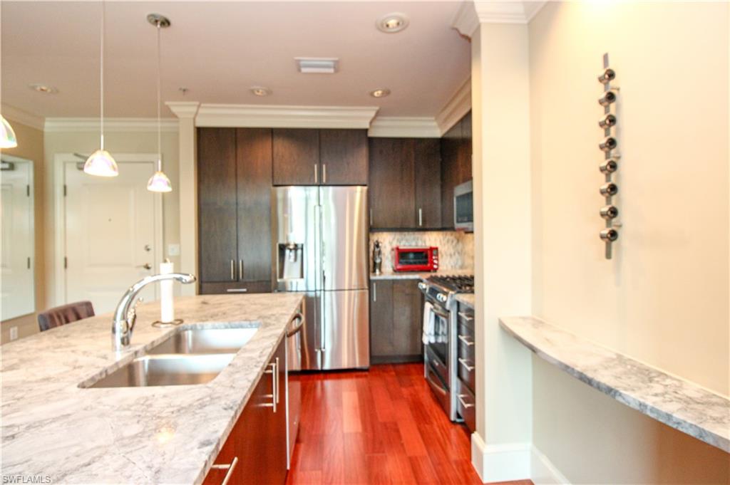 9123 Strada Place, Unit 7410 Naples, FL 34108 - Photo 28 of 50 Kitchen featuring dark hardwood / wood-style floors, pendant lighting, appliances with stainless steel finishes, ornamental molding, and sink