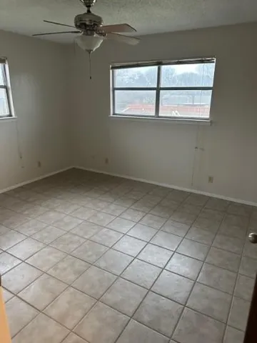 an empty room with a ceiling fan and window