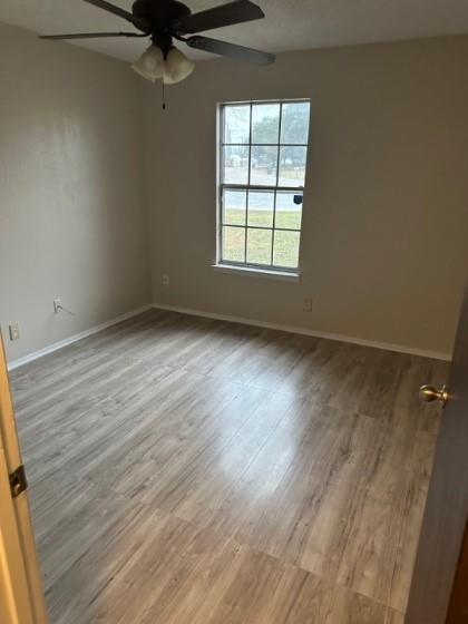 409 Skyline Circle Lorena, TX 76655 - Photo 8 of 16 an empty room with wooden floor fan and windows