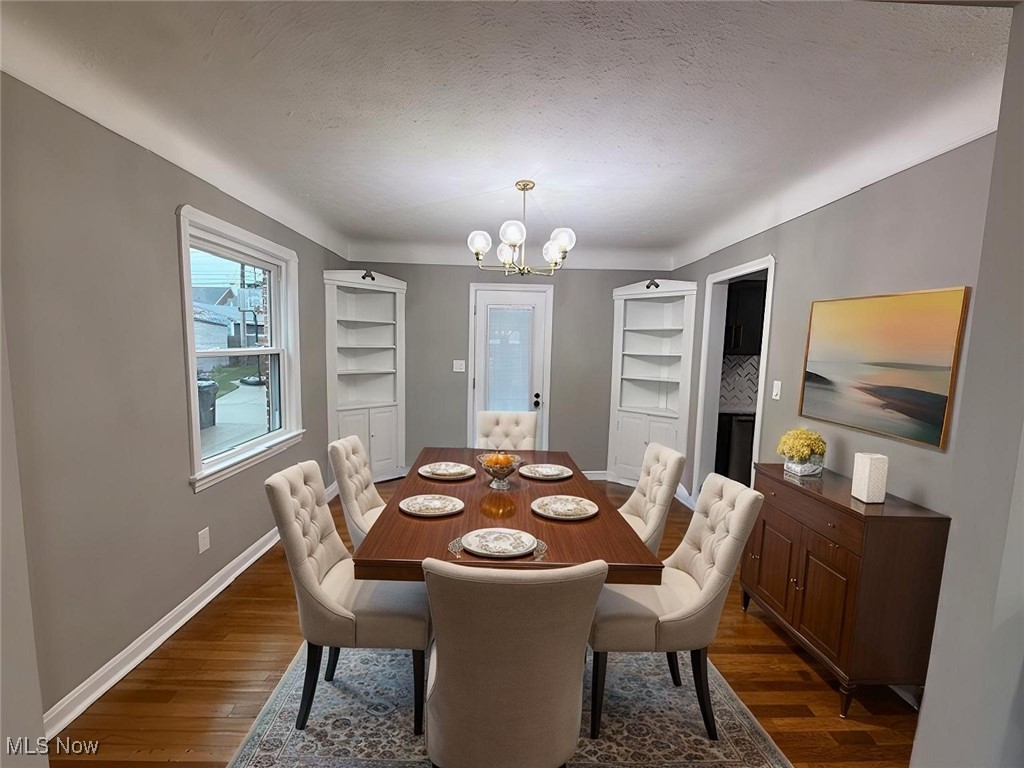 6807 Gerald Avenue Parma, OH 44129 - Photo 4 of 25 Dining area featuring dark wood finished floors, an inviting chandelier, baseboards, and a textured ceiling virtually staged