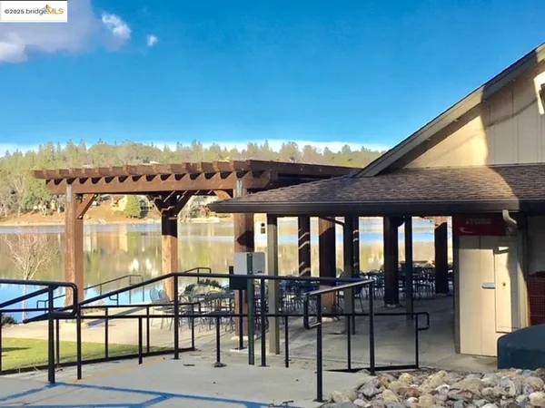 a view of swimming pool with seating area and trees in the background