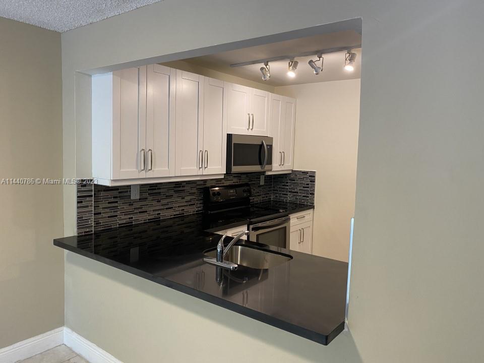 721 North Pine Island Road, Unit 304 Plantation, FL 33324 - Photo 2 of 22 a kitchen with granite countertop a stove a microwave and sink
