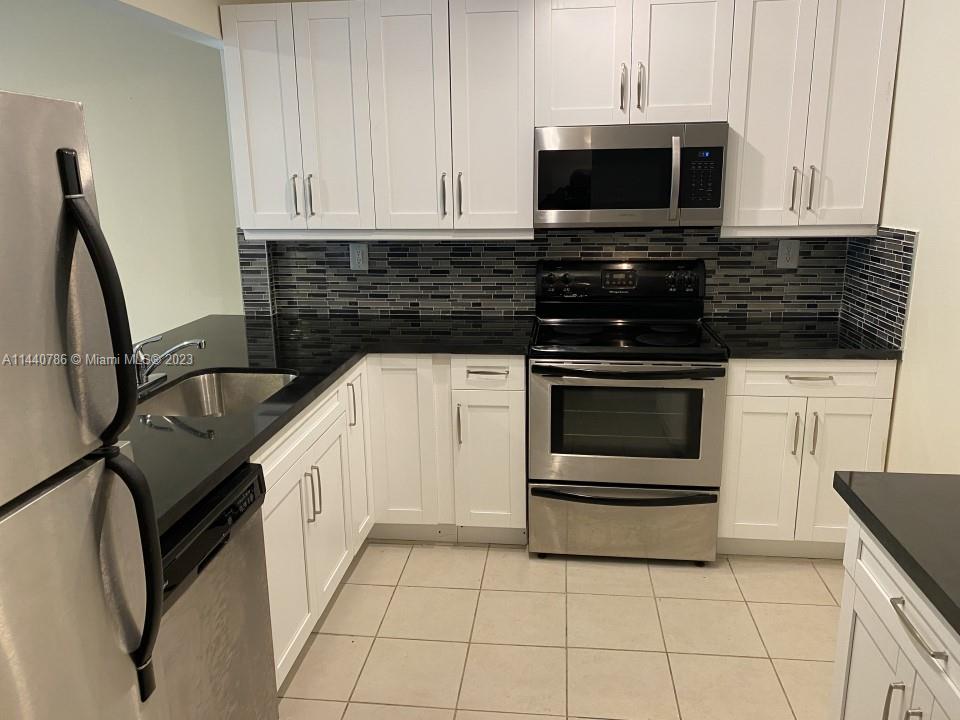 721 North Pine Island Road, Unit 304 Plantation, FL 33324 - Photo 3 of 22 a kitchen with granite countertop a stove sink and microwave