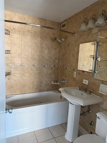 a bathroom with a sink and mirror with bathtub