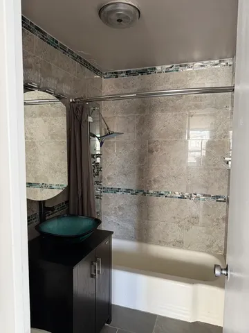 a bathroom with a granite countertop shower a sink and vanity