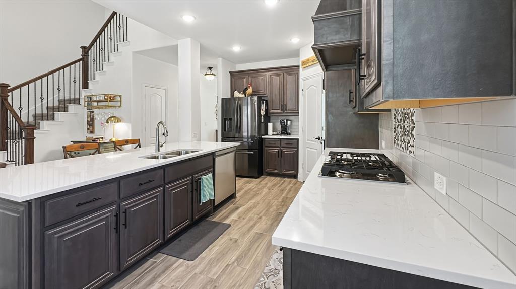 5216 Troupe Road McKinney, TX 75071 - Photo 10 of 40 Contemporary kitchen featuring white countertops, dark wood-finish cabinetry, stainless steel appliances, a gas cooktop, and subway tile backsplash