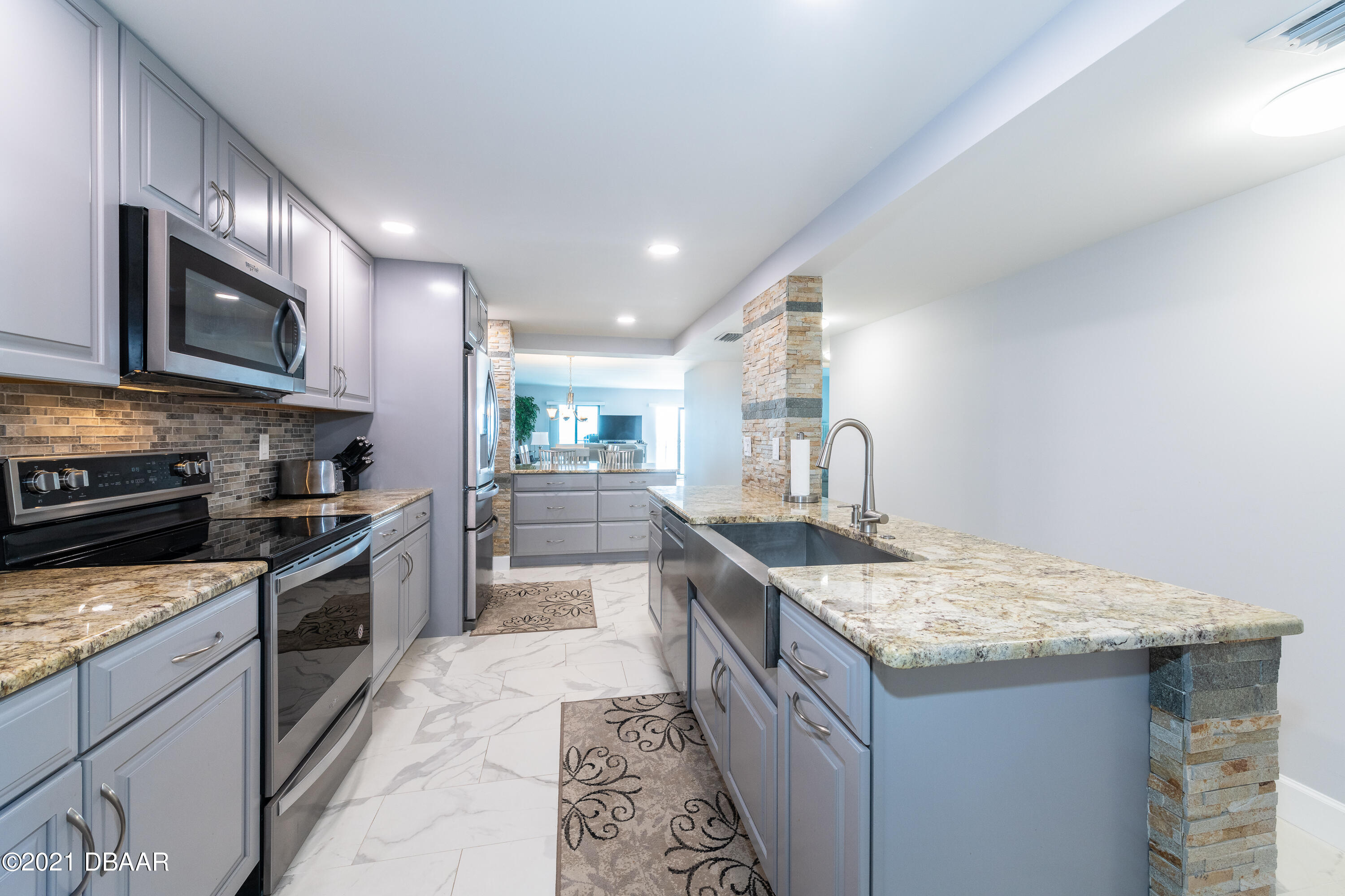 1275 Ocean Shore Boulevard, Unit 307 Ormond Beach, FL 32176 - Photo 4 of 24 a kitchen with stainless steel appliances granite countertop a stove top oven a sink dishwasher a dining table and chairs
