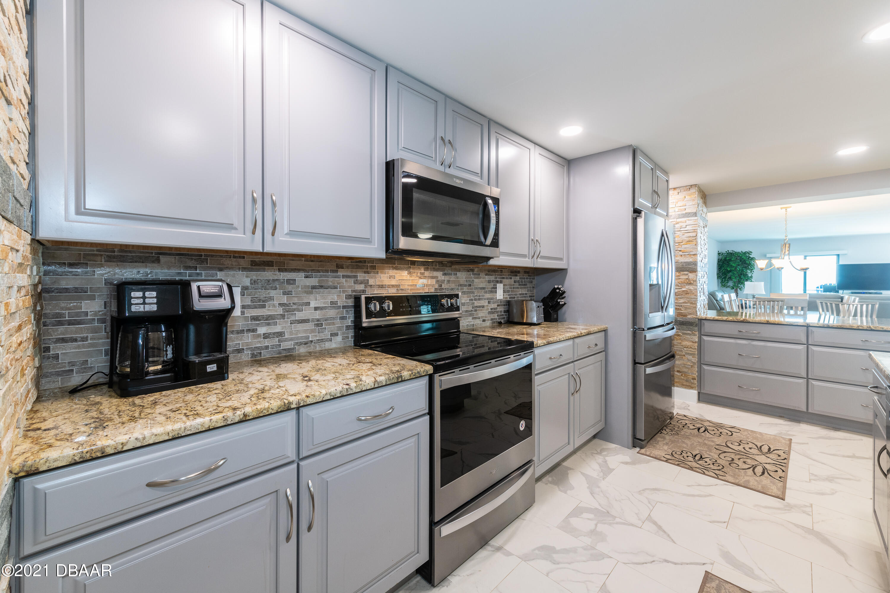 1275 Ocean Shore Boulevard, Unit 307 Ormond Beach, FL 32176 - Photo 5 of 24 a kitchen with stainless steel appliances granite countertop a stove a sink and a microwave