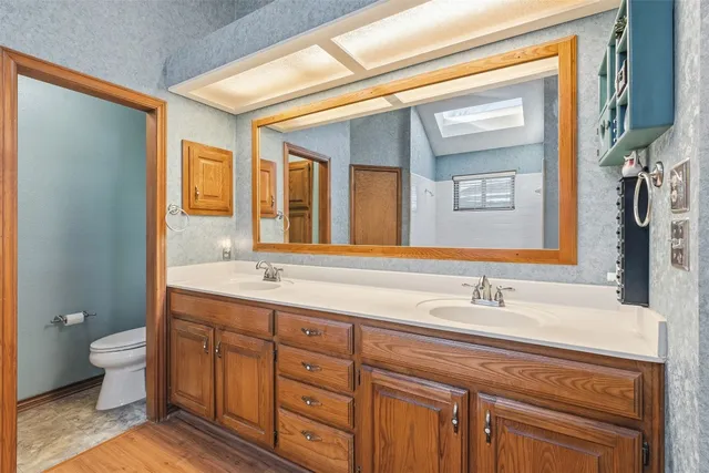 a bathroom with a double vanity sink toilet and a mirror