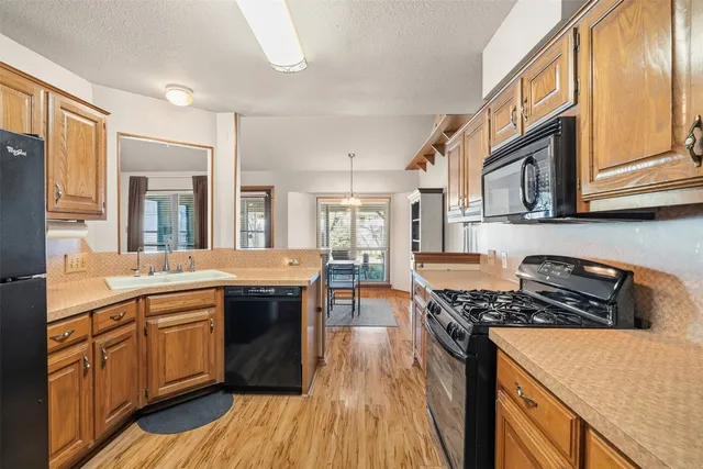 a kitchen with stainless steel appliances granite countertop hardwood floor sink stove and wooden cabinets